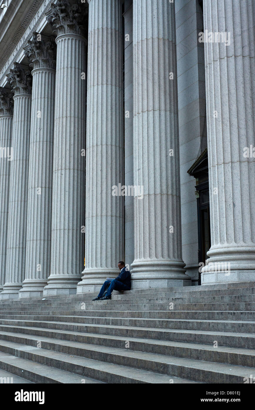 Man alone sitting on the steps of the post office in Lower Manhattan. Stock Photo