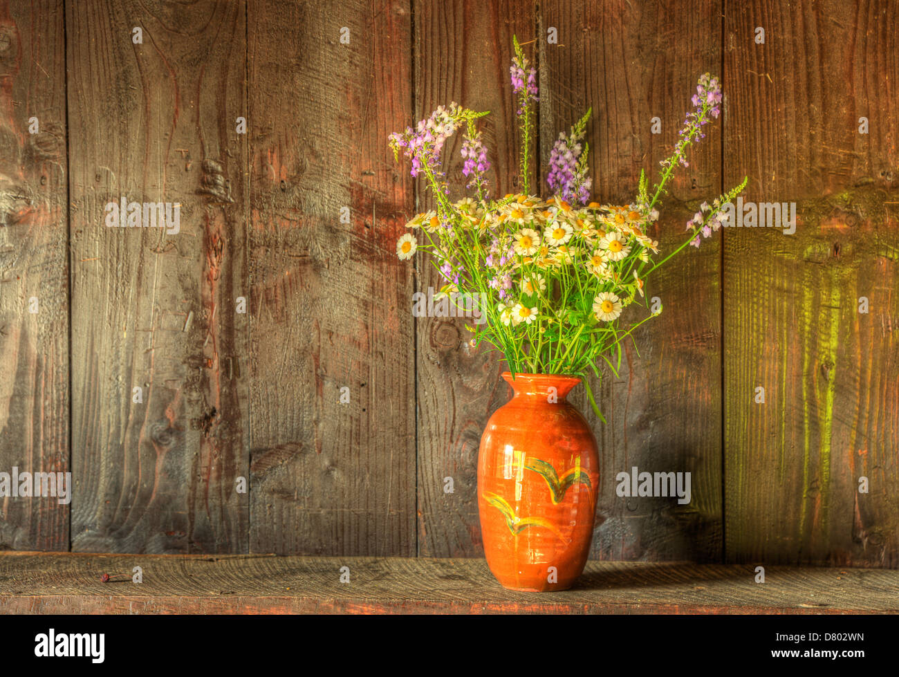 Still life image of dried flowers in rustic vase against weathered ...