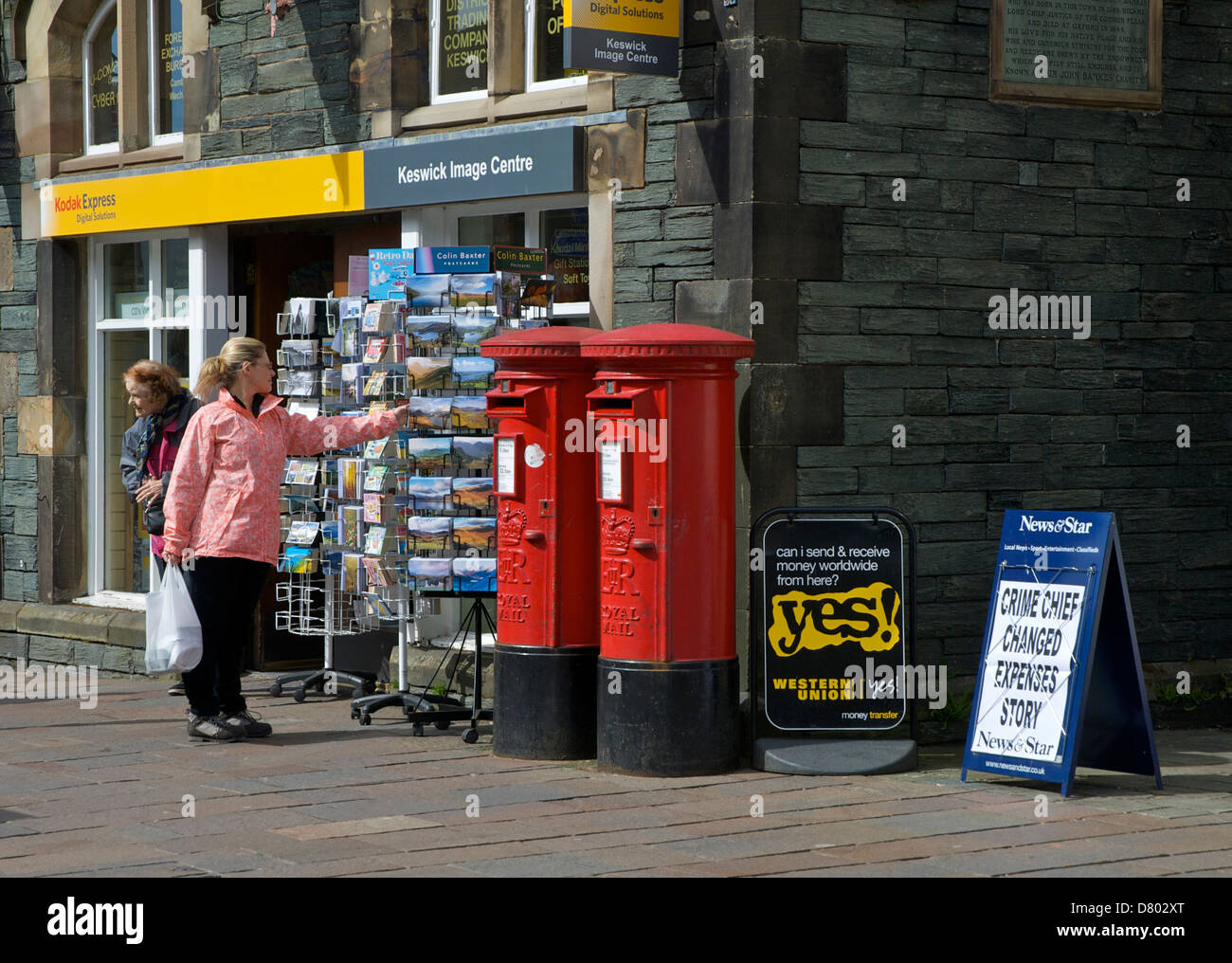 Woman browsing through postcards outside the post office, Keswick, Lake District National Park, Cumbria, England UK Stock Photo
