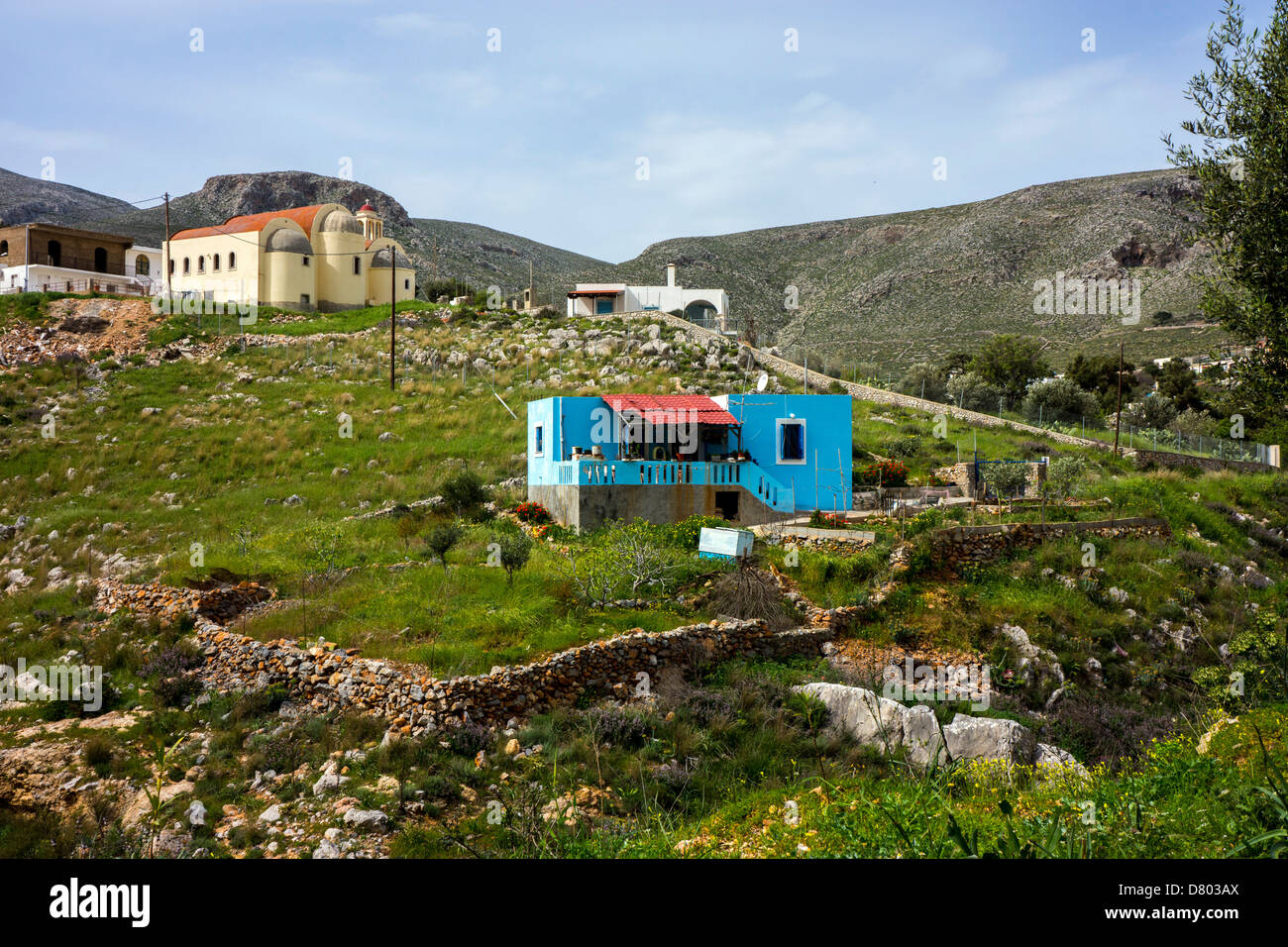 Small blue Greek house surrounded by grassy fields Stock Photo