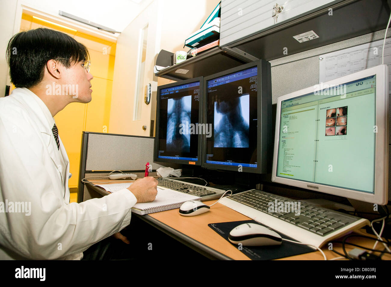 A doctor views x-ray images, as part of patient diagnosis, in the Reading Room, in a Medical Centre. Stock Photo