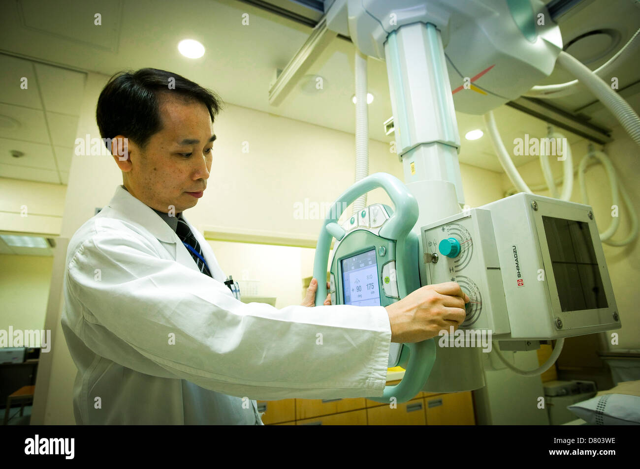 A radiologist adjusts an X-ray machine prior to use. Stock Photo
