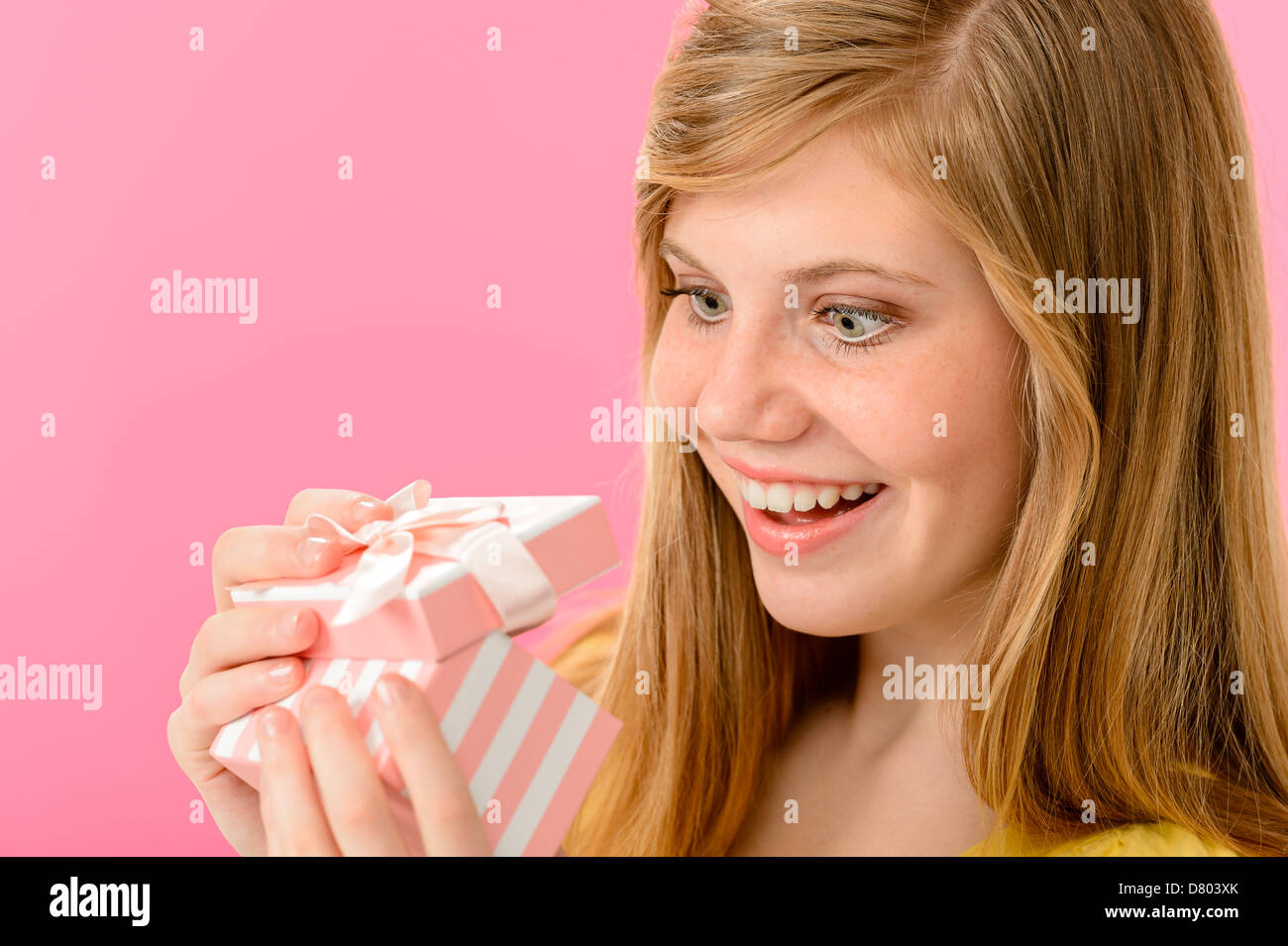 Elated girl opening gift isolated on pink background Stock Photo
