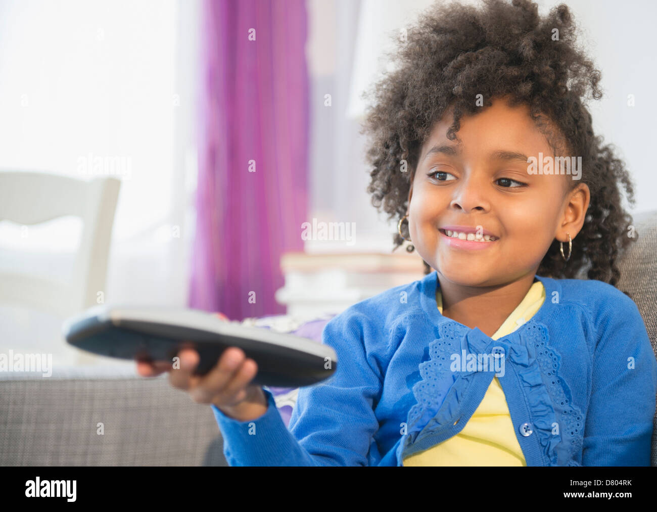 African American girl watching television on sofa Stock Photo