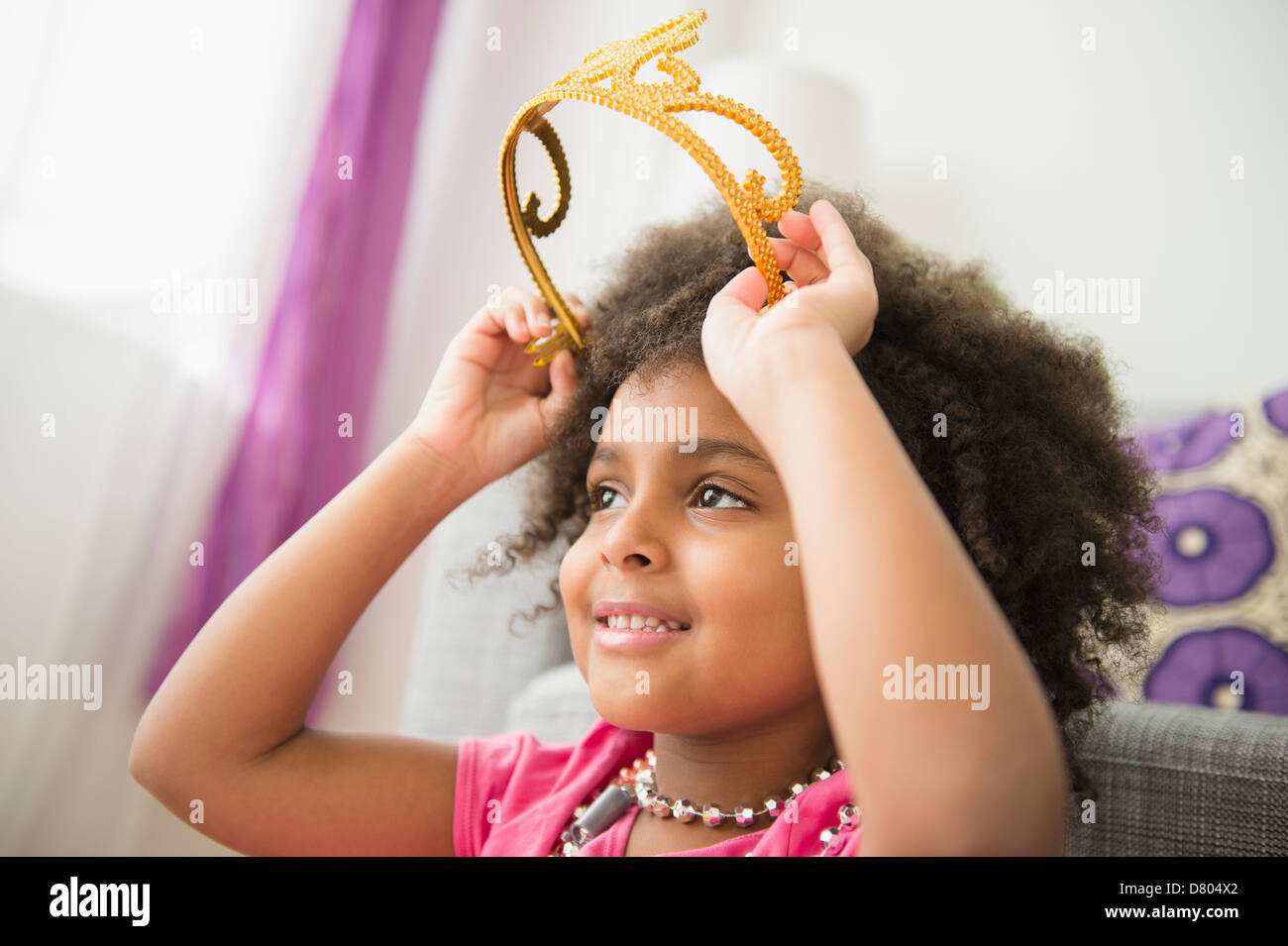 African American girl putting on toy crown Stock Photo