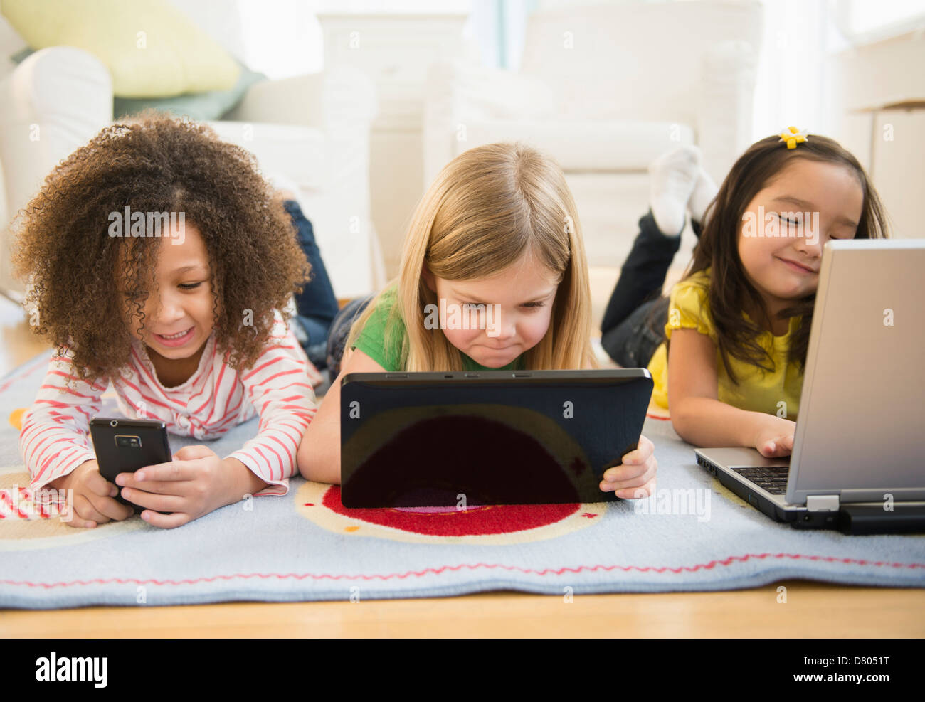 Girls using technology on carpet Stock Photo