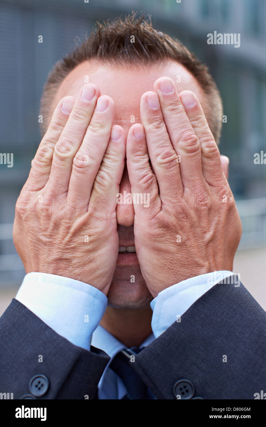 Business man covering his face with his both hands Stock Photo