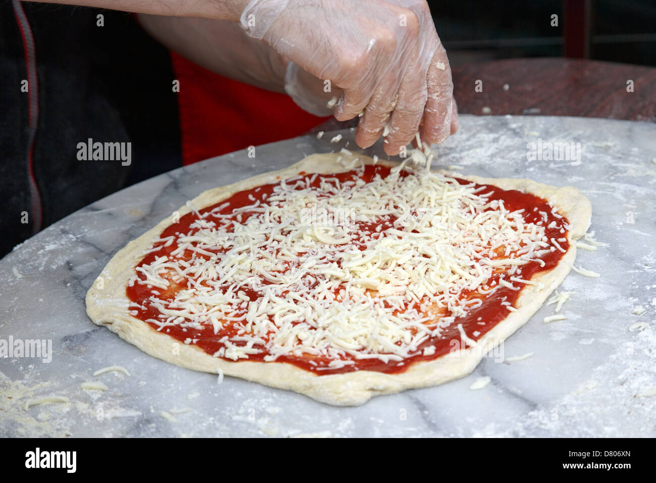 man making pizza spreading cheese over pizza Stock Photo