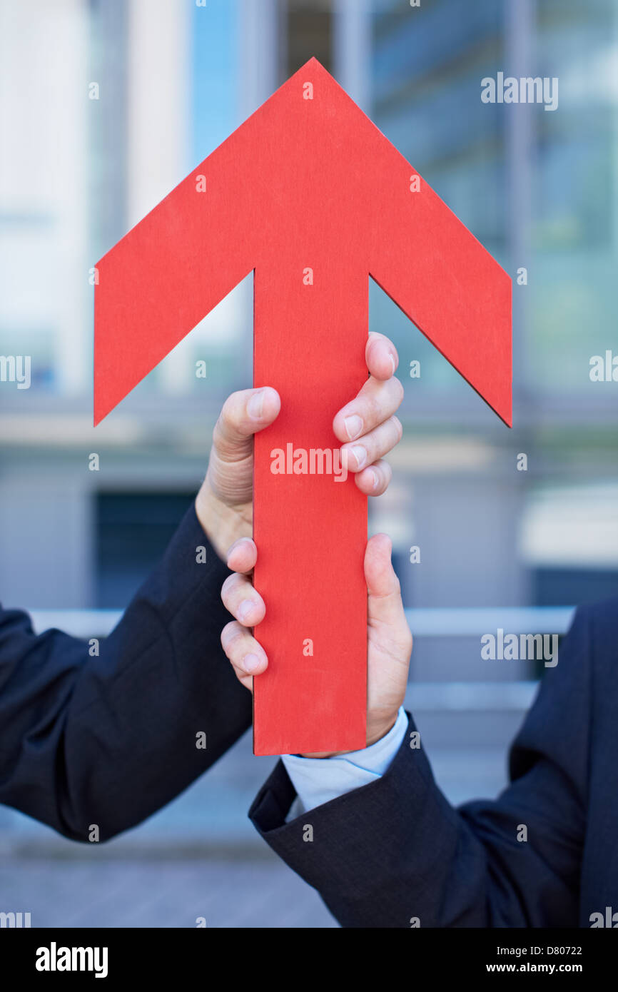Two hands holding a red arrow pointing up Stock Photo - Alamy
