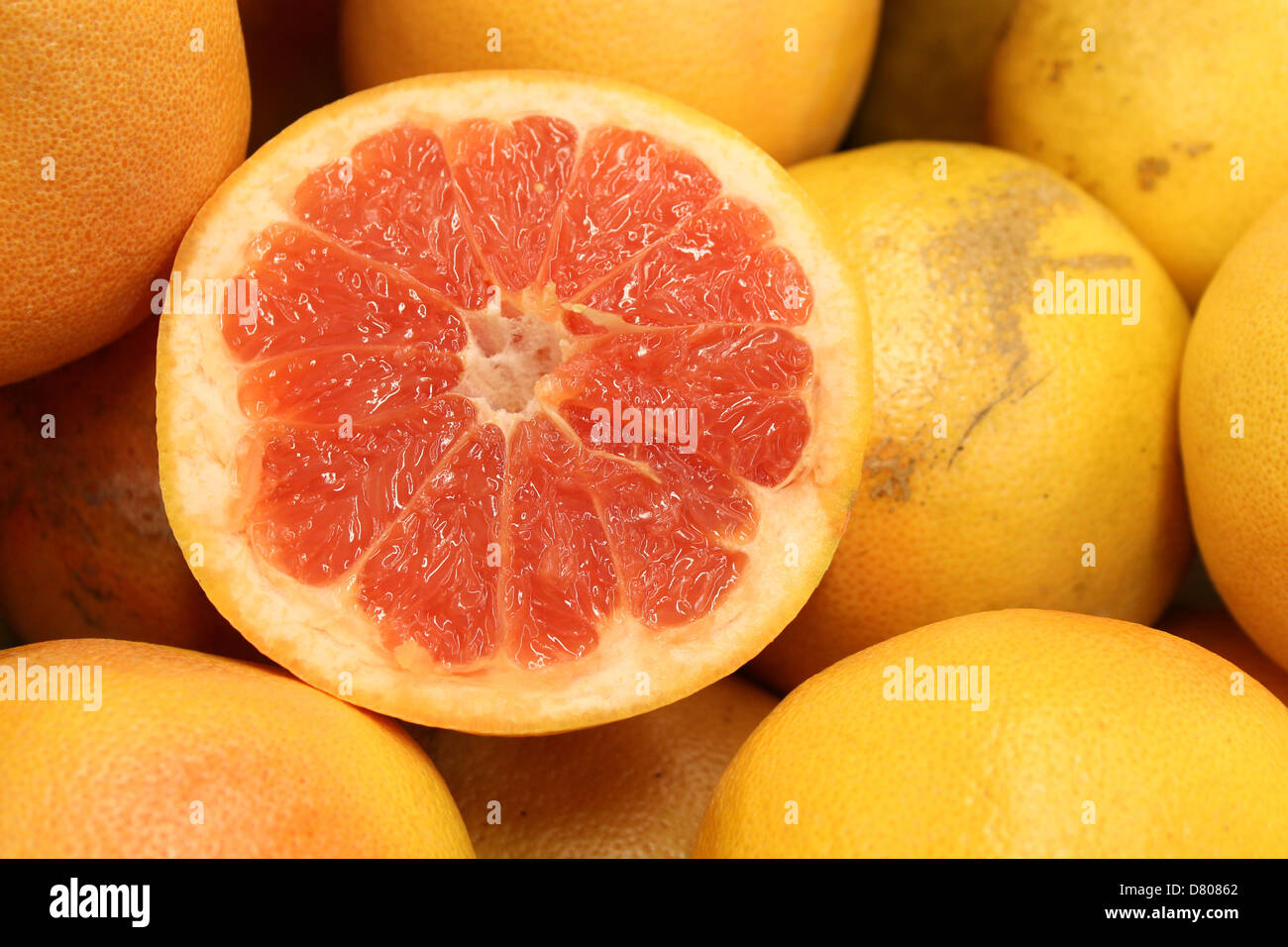 Half grapefruit cut and displayed on fresh whole grapefruit to show how