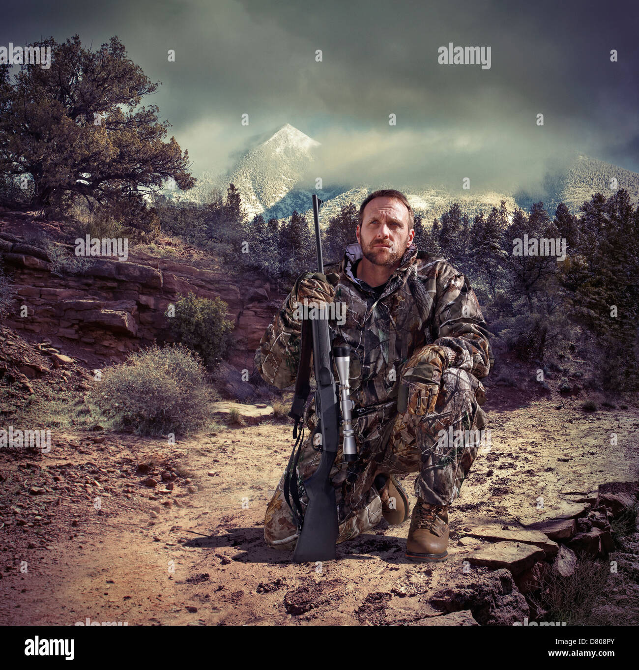 Soldier holding gun in dry rural landscape Stock Photo