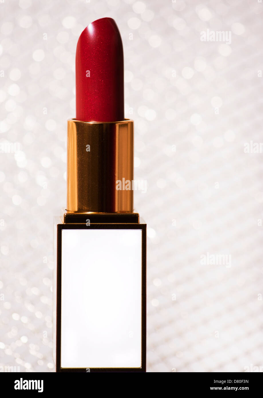 close up of a red lipstick in a white and gold holder against a gold background Stock Photo