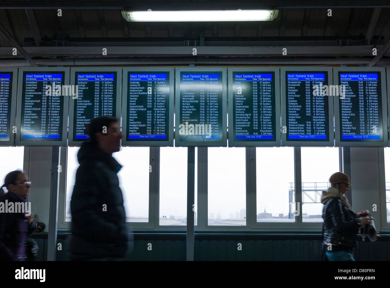 passengers walking by electronic train time display board at Clapham Junction Stock Photo