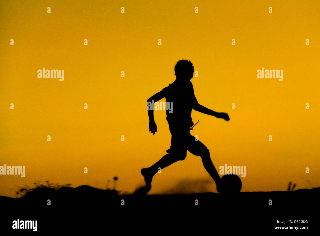 A young boy plays football during the sunset on the beach in Uruau, a small fishing community in the northeastern Brazil. Stock Photo