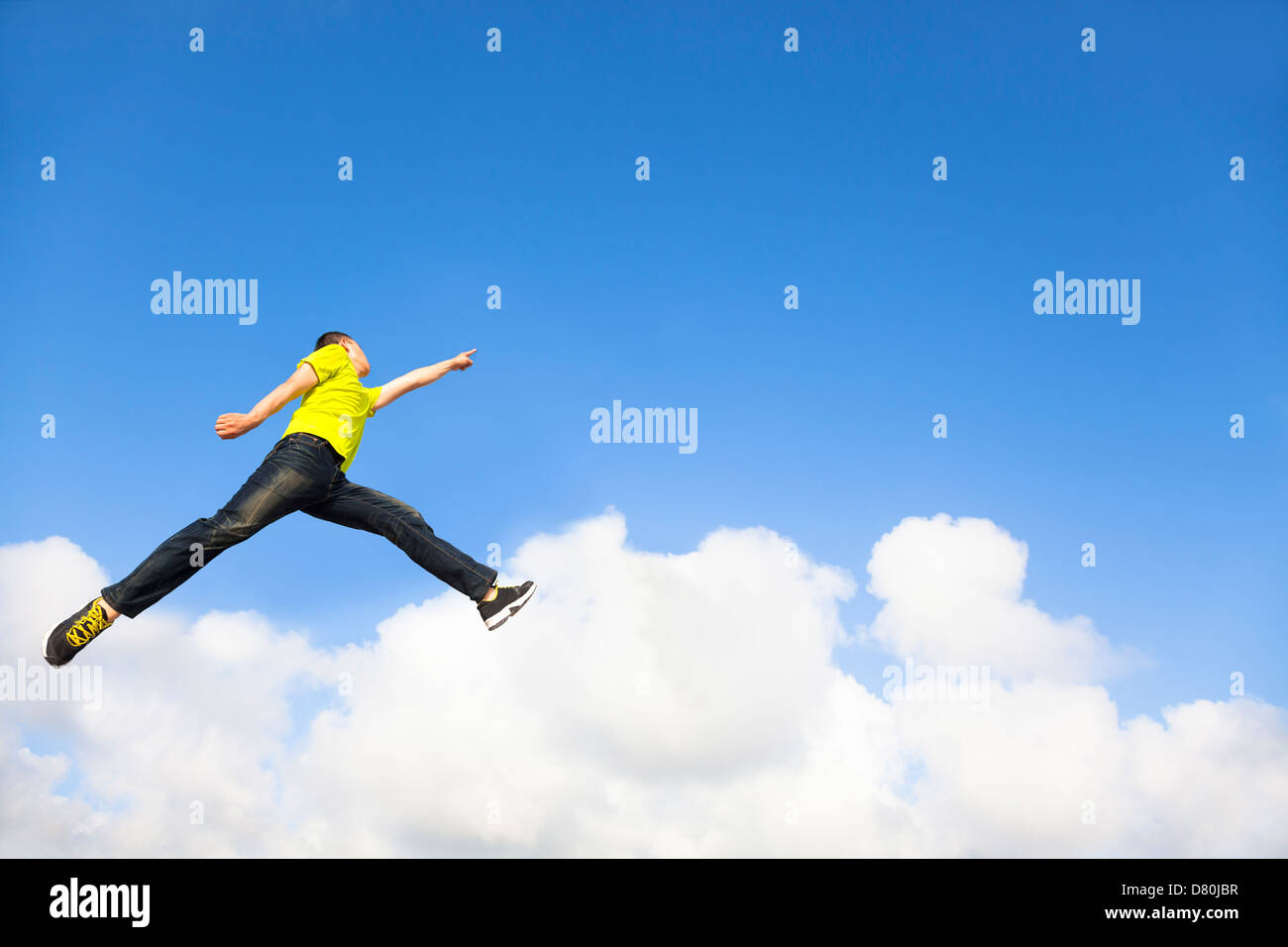happy young man jumping and pointing to sky Stock Photo