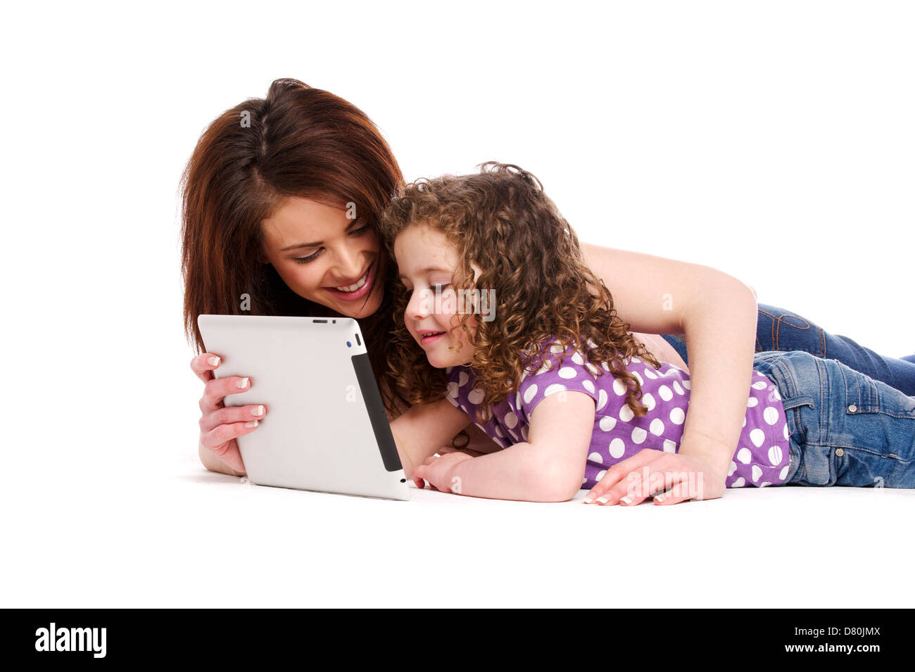 Mother sat with a little girl on her knee playing on a computer tablet isolated on a white background Stock Photo