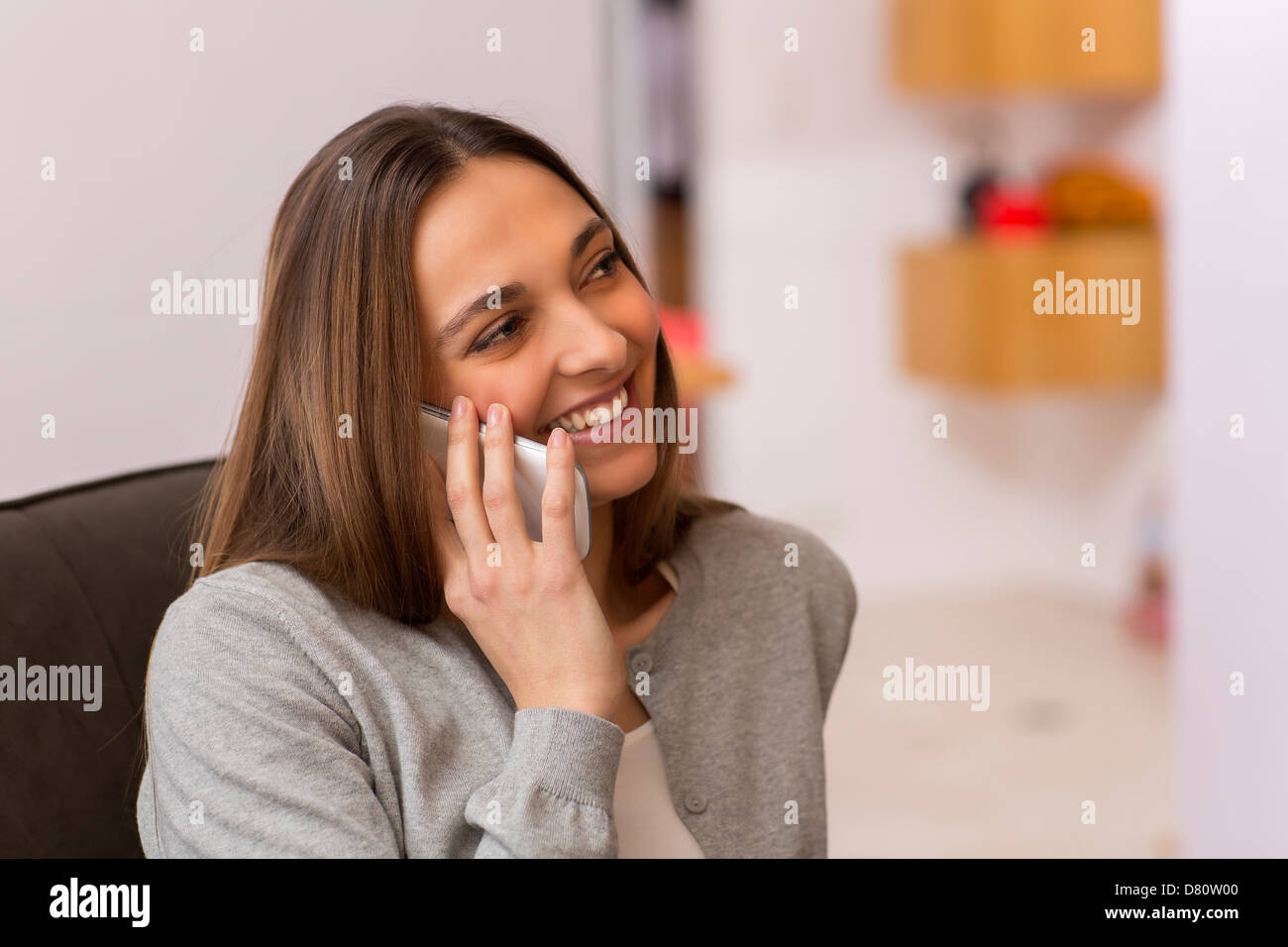Pretty female using white mobile phone at home talking to friends Stock Photo