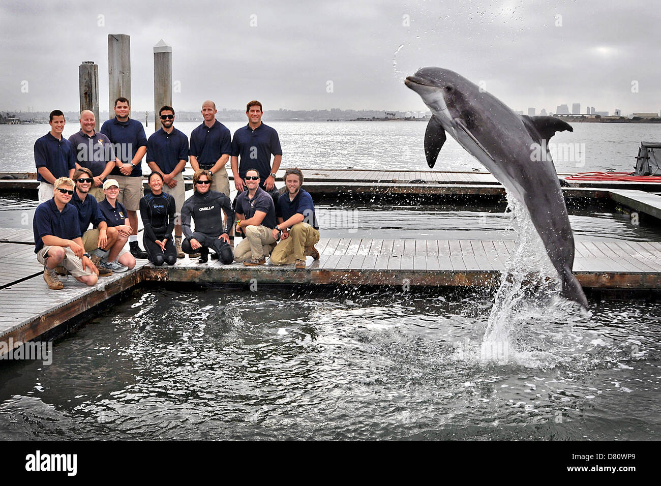 San Diego, California, USA. 15th May 2013. US Navy sailors with the Space and Naval Warfare Systems Center Pacific Marine Mammal Team pose with a specially trained Atlantic bottle-nosed dolphin after recovering a Howell torpedo May 15, 2013. The Howell torpedo was the first self-propelled torpedo used by the US Navy in 1870. Credit:  US Navy Photo / Alamy Live News Stock Photo