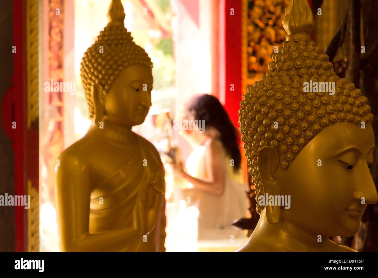 PHUKET, THAILAND APRIL 28 2013: AThai woman exits a temple building after a Wai Phra offering at Wat Chalong. Stock Photo