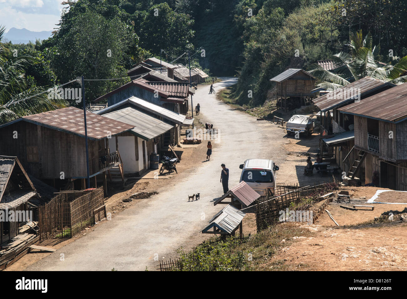 NORTHERN LAOS — A small, remote village nestles against the rugged, mountainous terrain of northern Laos, its modest dwellings clustered along a winding dirt road. This scene captures the essence of rural life in one of Southeast Asia's least developed regions, showcasing traditional architecture and the challenging landscape that shapes daily existence in this remote corner of the country. Stock Photo