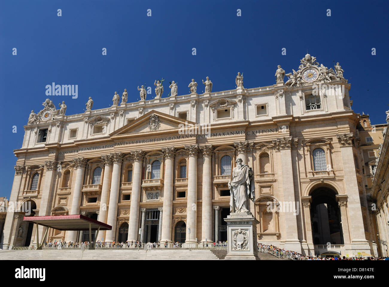 Statue of St Paul with crowds at Saint Peters Papal Basilica in Rome Italy with blue sky Stock Photo