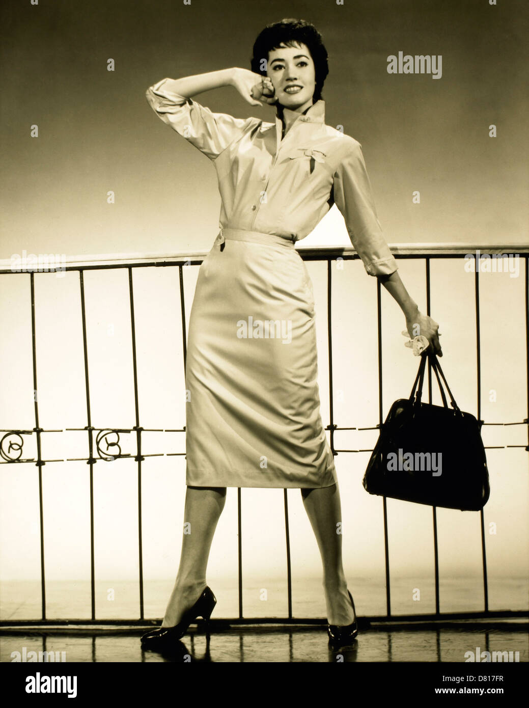 Female Model Posing in Fashionable Dress and Holding Handbag, Circa 1950 Stock Photo