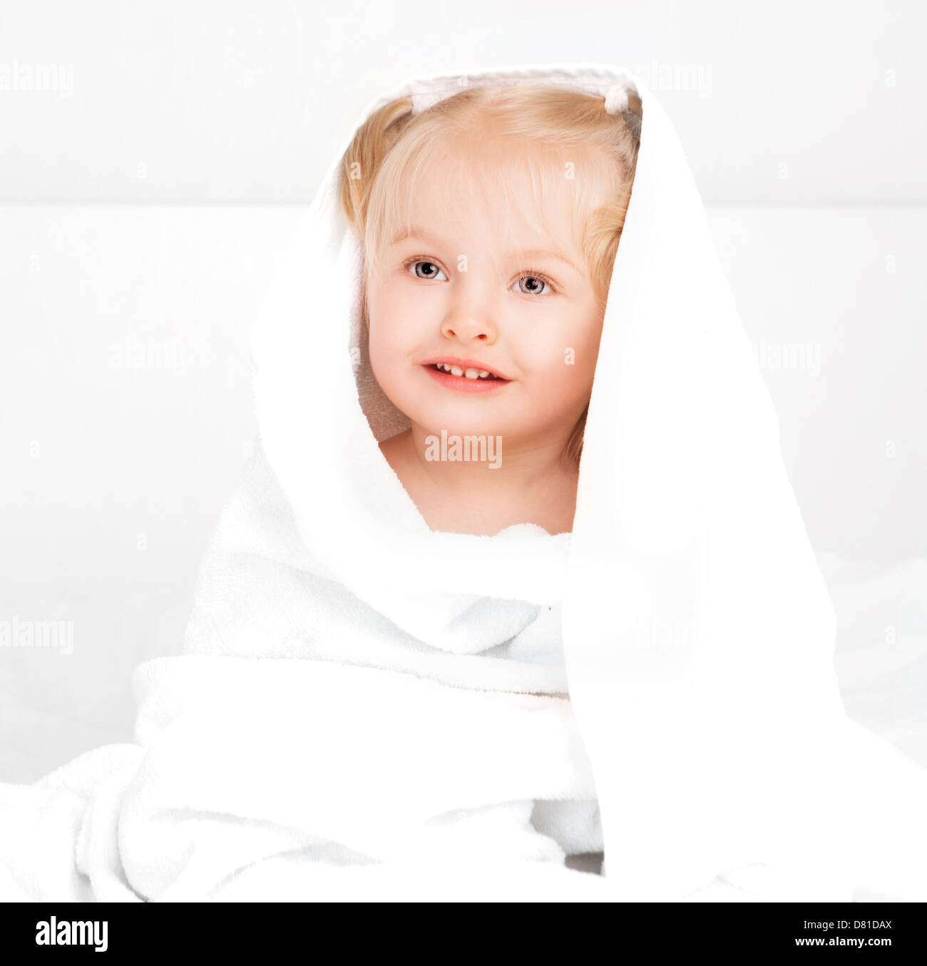 two year old girl wrapped into towel in bed at home Stock Photo Alamy