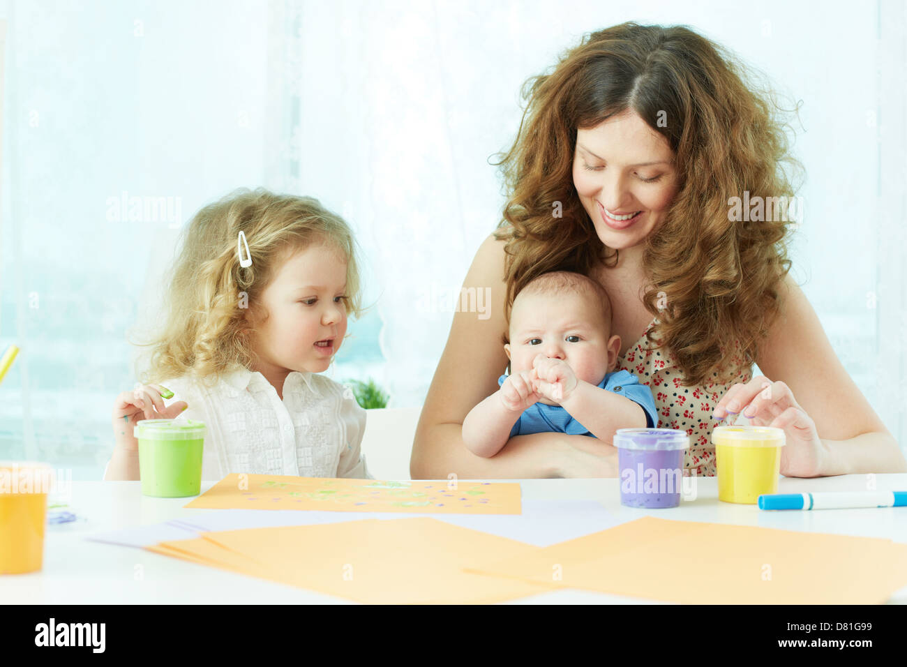 Happy mother and kids painting with gouache Stock Photo