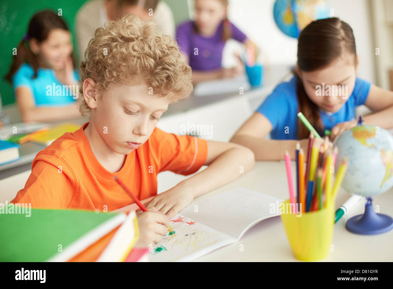 Portrait of cute schoolboy drawing at workplace during lesson Stock ...