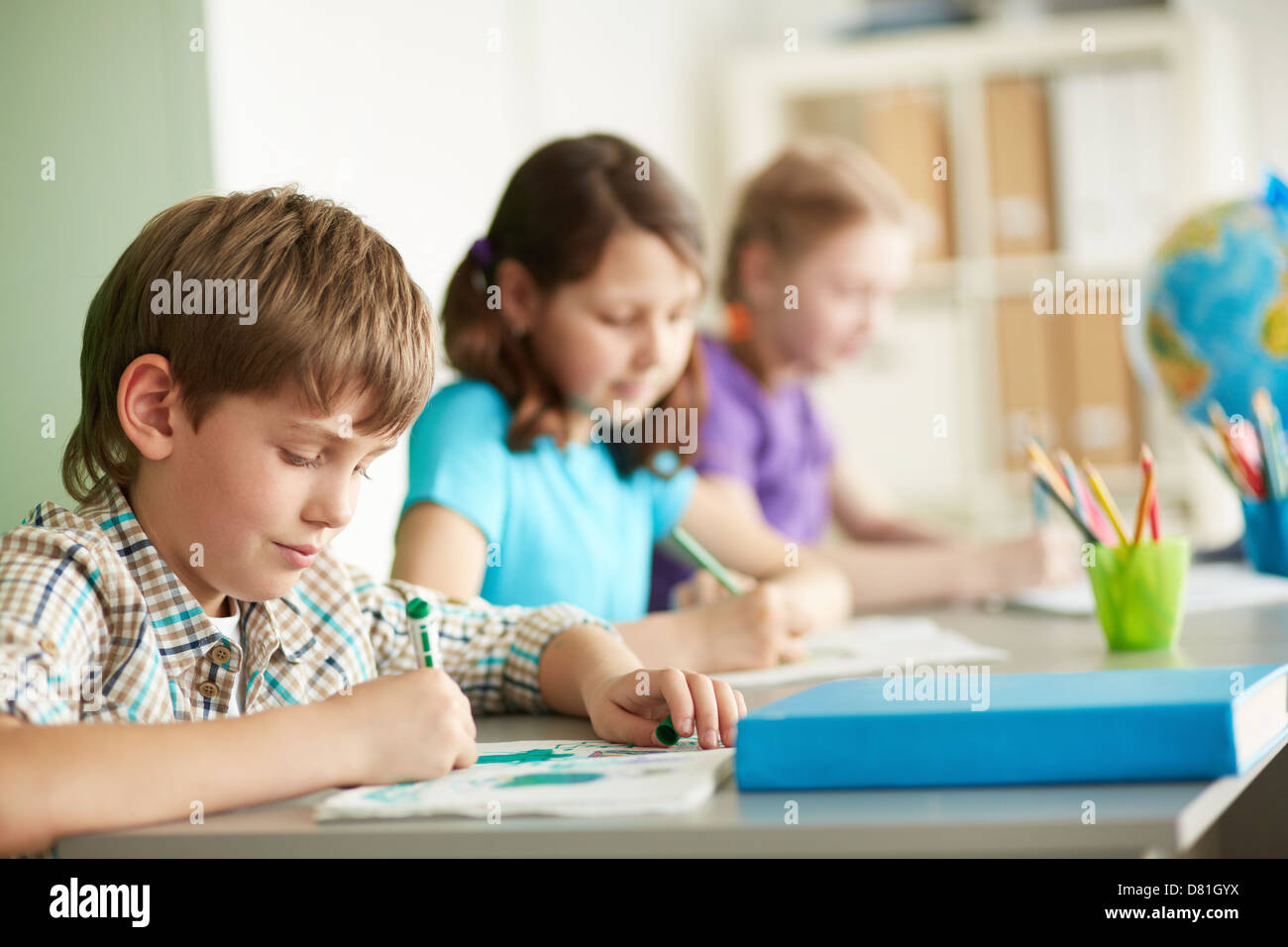 Portrait of cute schoolboy drawing at workplace during lesson Stock ...