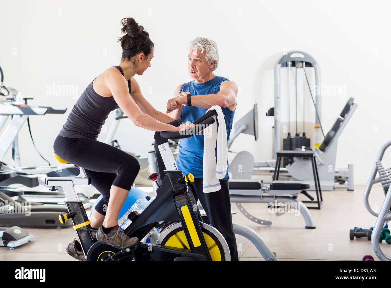Hispanic trainer working with woman in gym Stock Photo