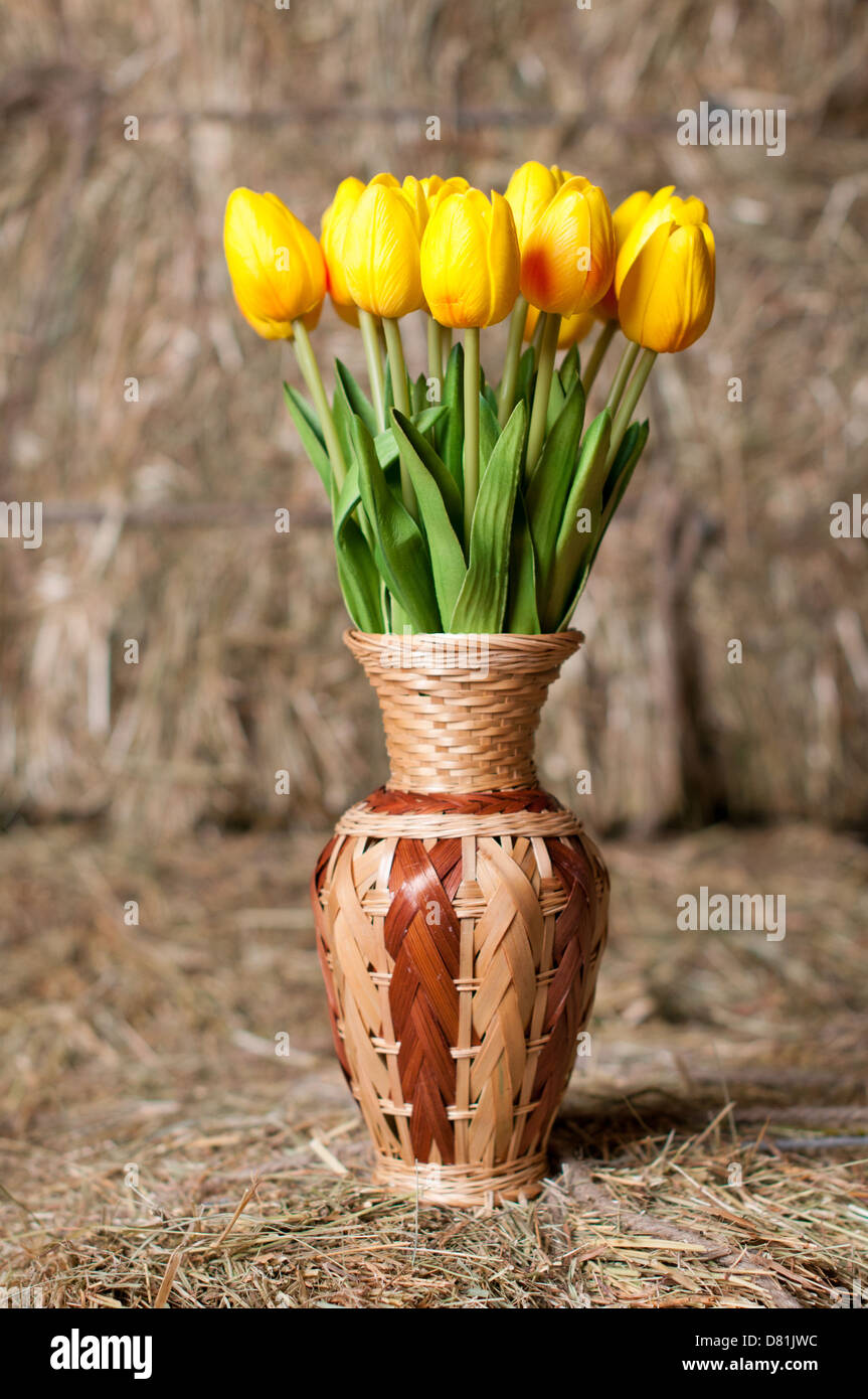 Yellow tulips in a wicker vase on background of hay Stock Photo - Alamy