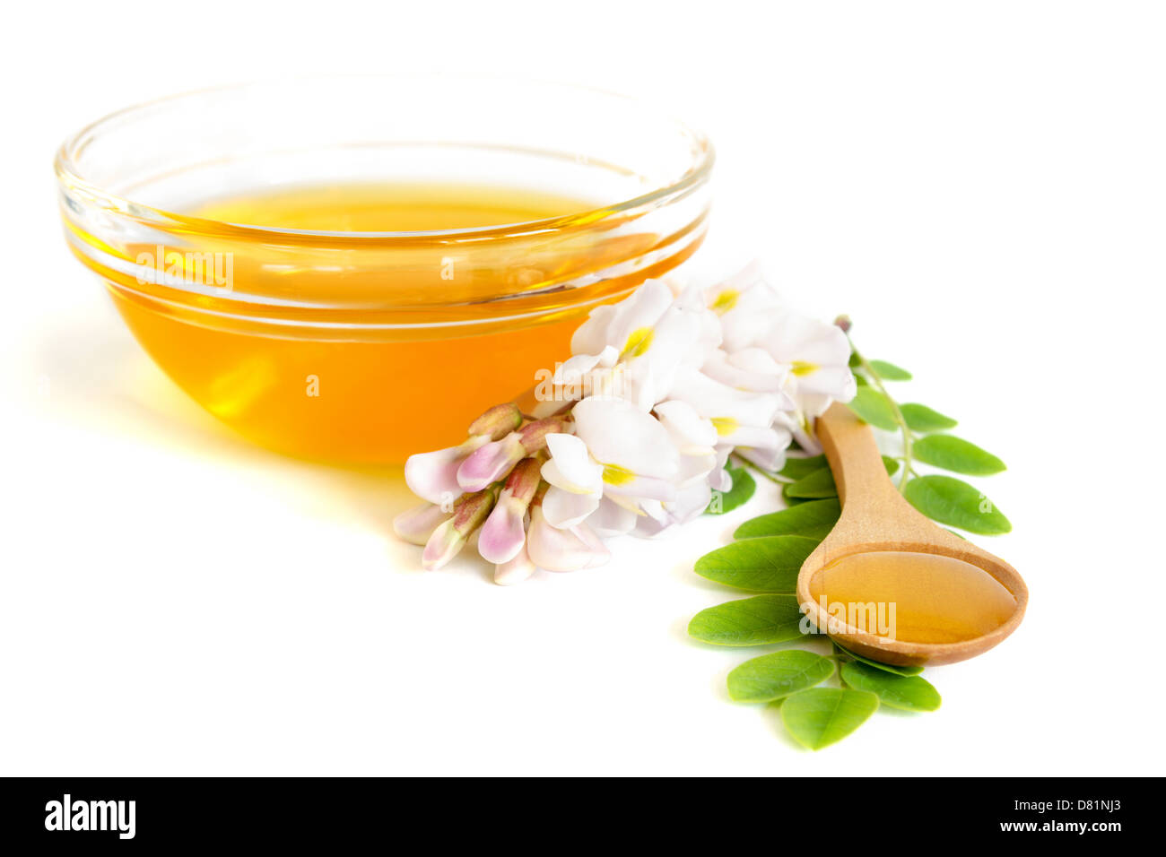 Honey in spoon with acacia and glass bowl on white background Stock Photo