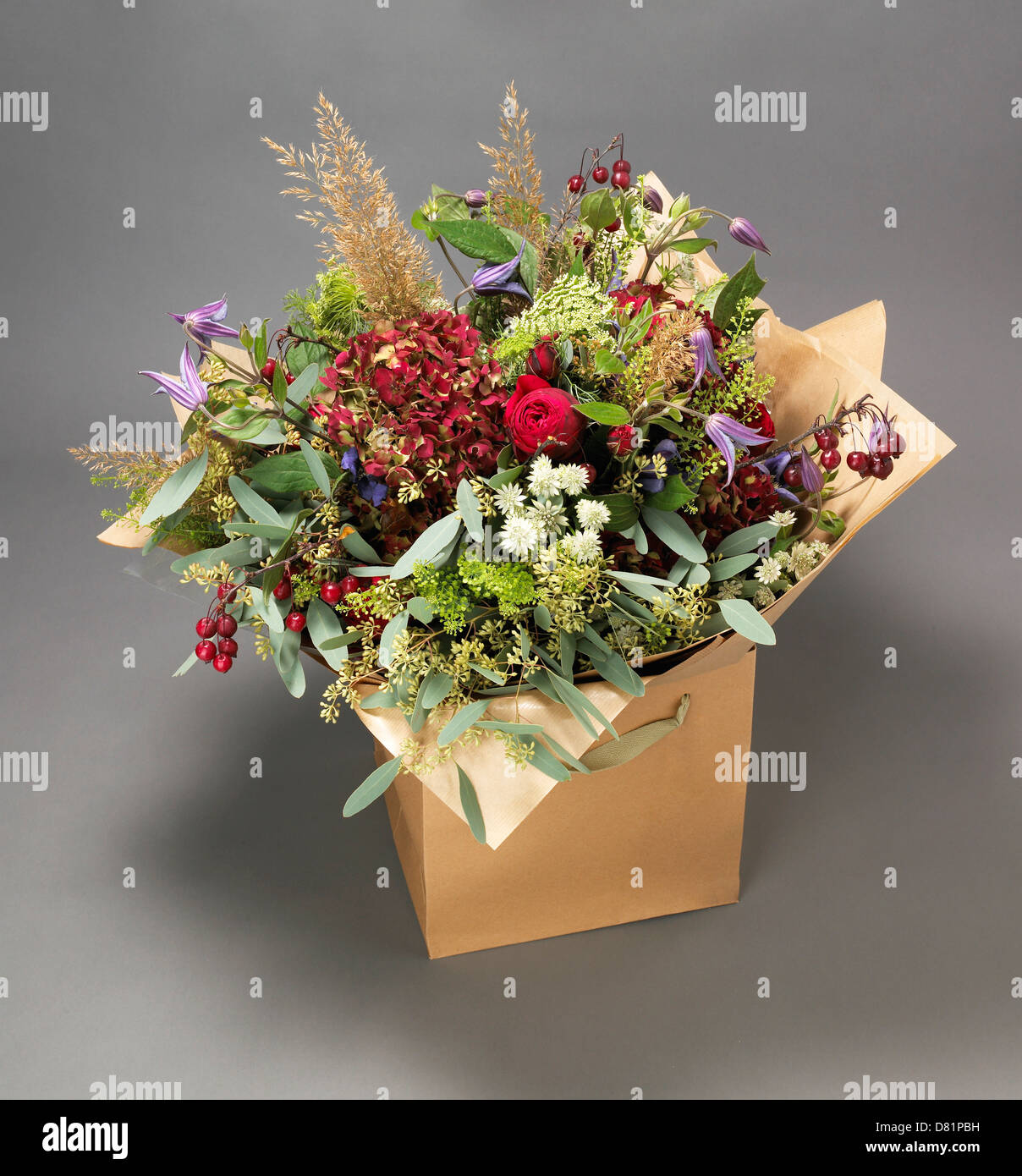 Large bunch of flowers including roses and meadow flowers displayed in a cardboard box on a grey background Stock Photo