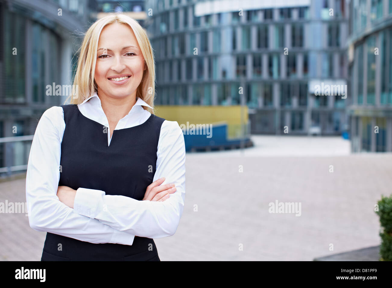 Smiling business woman with her arms crossed outside the office Stock ...
