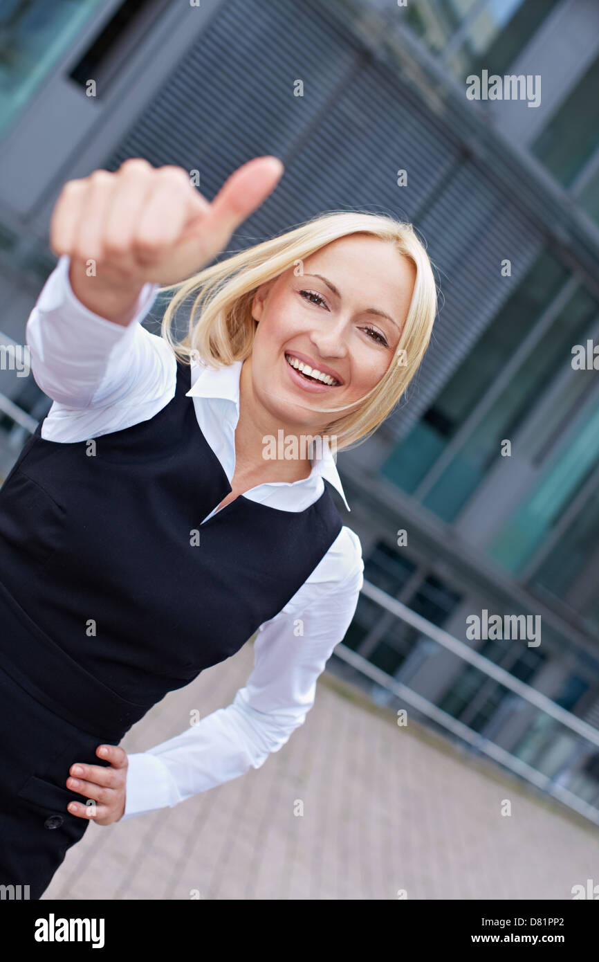 Attractive business woman in the city holding her thumbs up Stock Photo