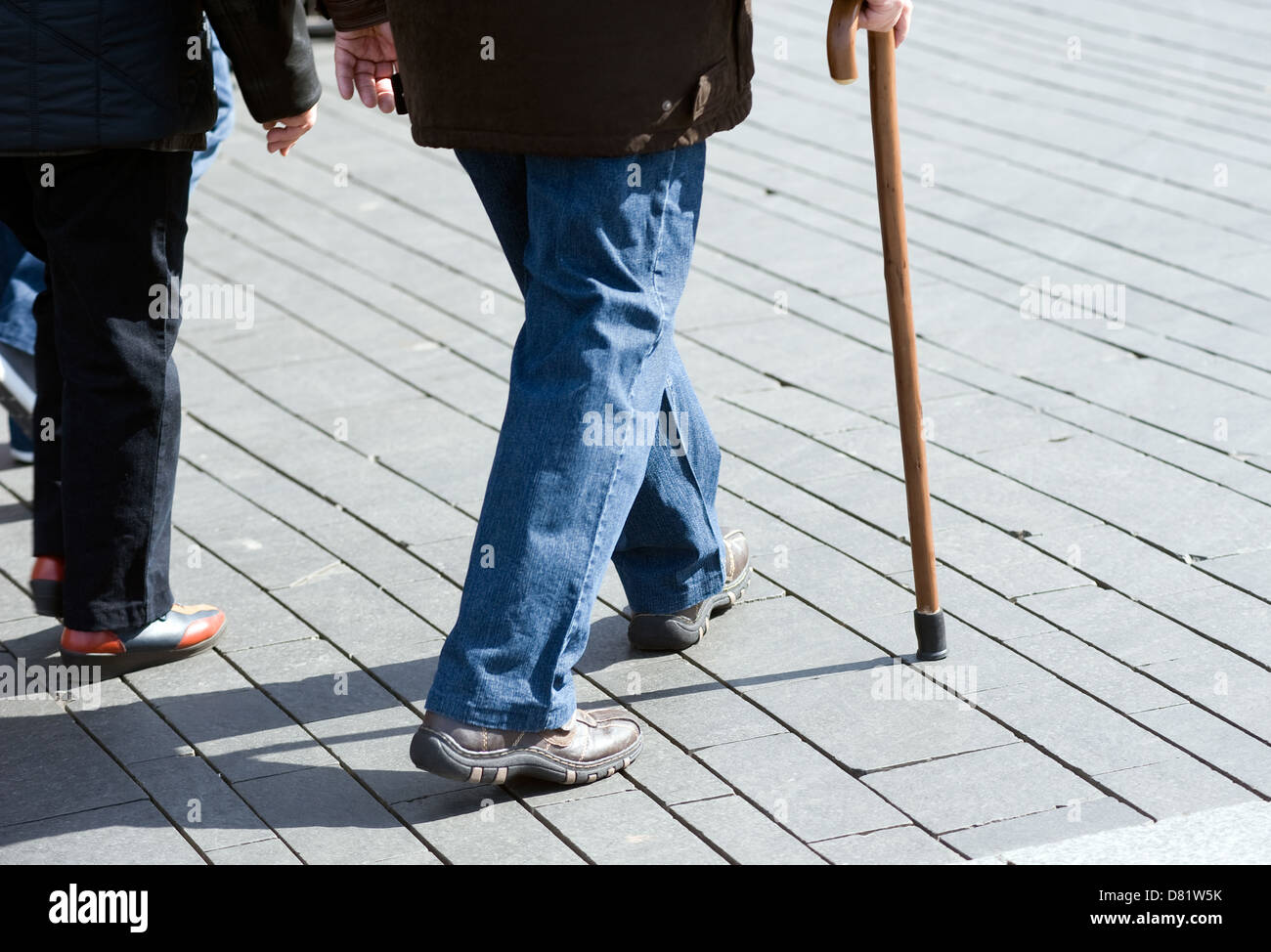 An old man walking on the street with a walking stick Stock Photo