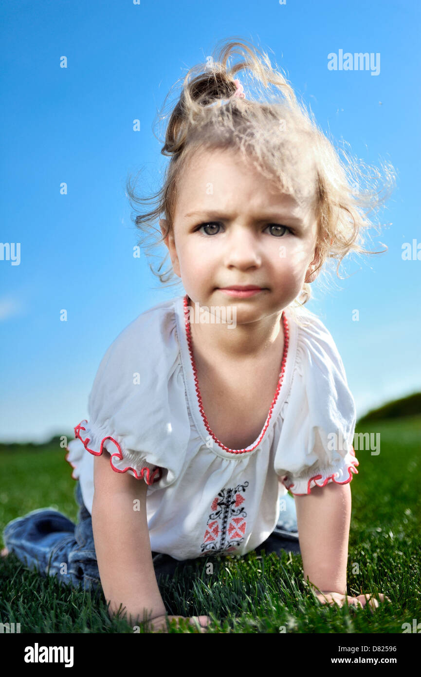 Curious baby girl crawling on the green grass in the park Stock Photo