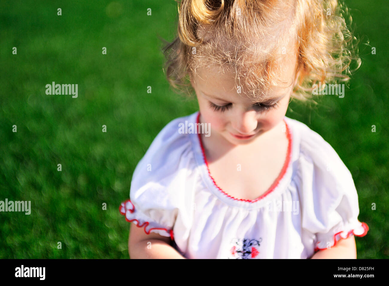 Portrait of beautiful baby girl on the lawn in summer park Stock Photo