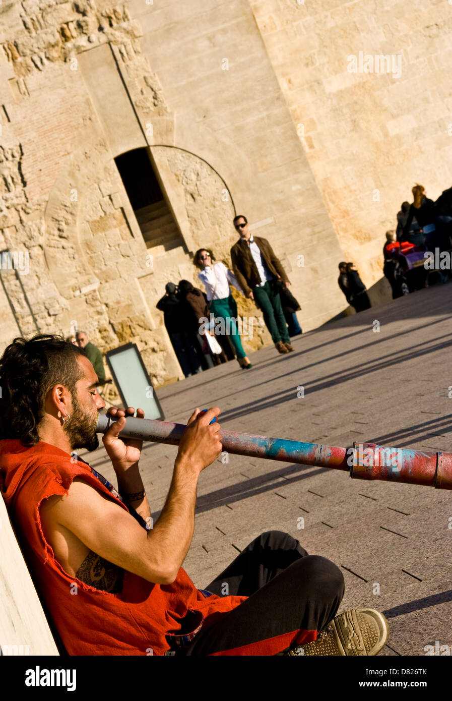 Busker street performer playing a didgeridoo on the Roman bridge ...