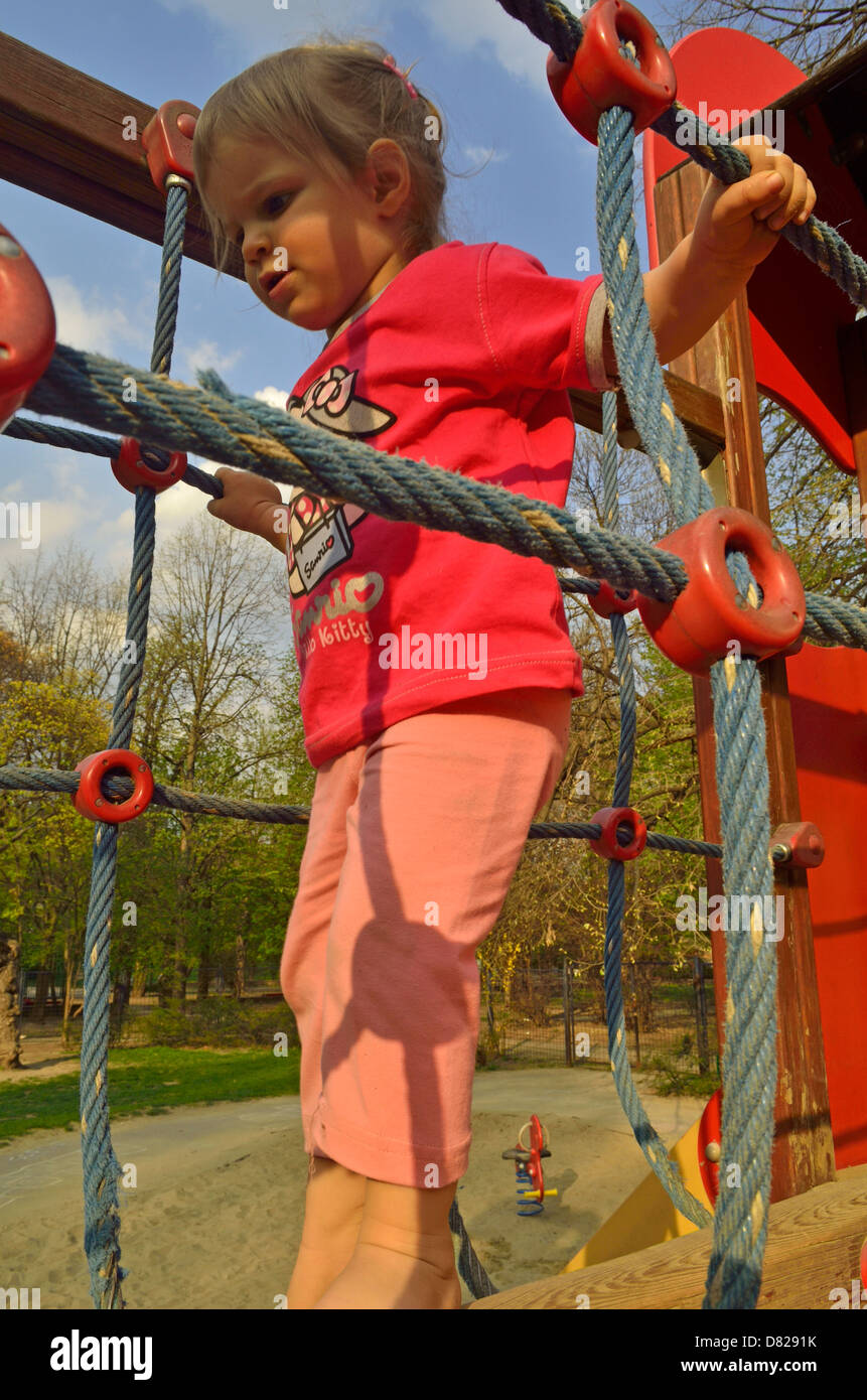 2 year old girl walk on jungle gym at playground Stock Photo