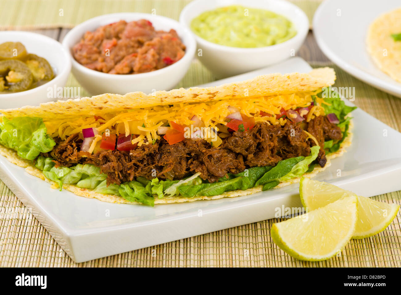 Beef Tacos - Mexican shredded beef tacos in soft corn tortillas served with lettuce, sour cream, grated cheddar cheese and salsa Stock Photo
