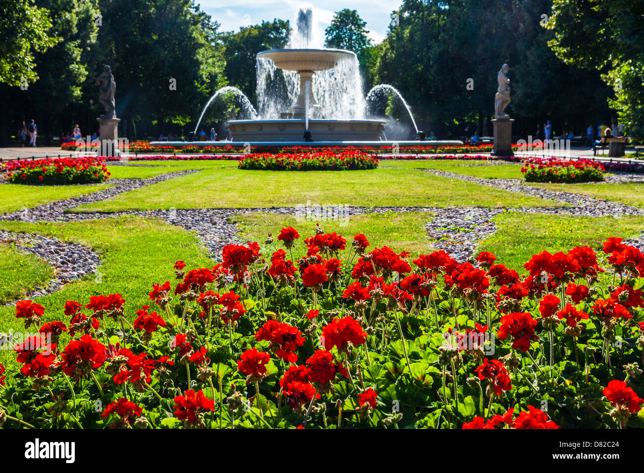Red geraniums in front of the fountain in Ogród Saski, Saxon Garden, the oldest public park in Warsaw, Poland. Stock Photo