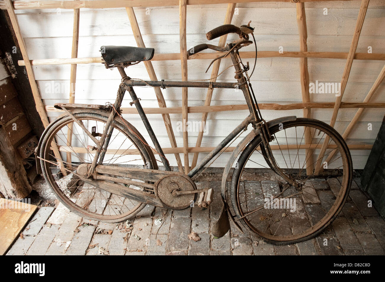 An old Bicycle leaning against a wall in an outbuilding. UK. Stock Photo