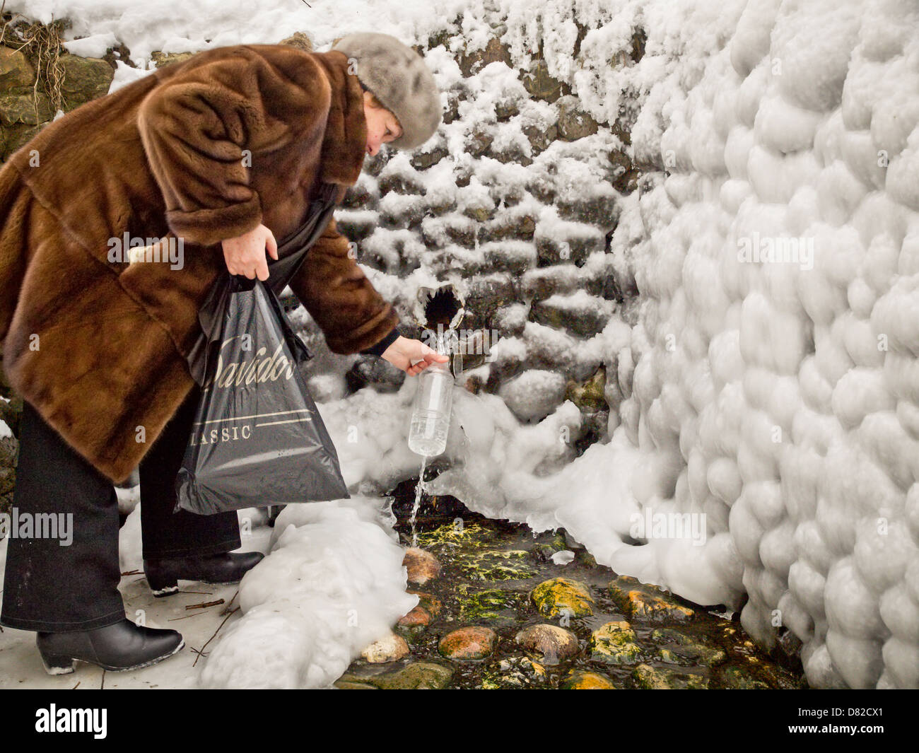 A Russian women taking drinking water at spring source in winter, Kolomenskoe, Moscow Stock Photo