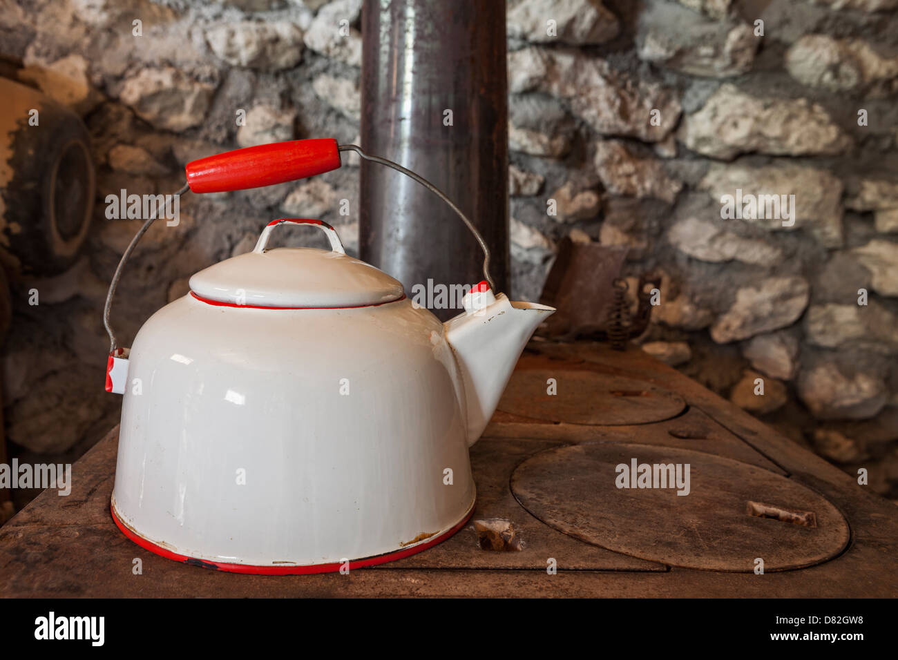 Antique metal tea kettle on top of wood burning stove Stock Photo