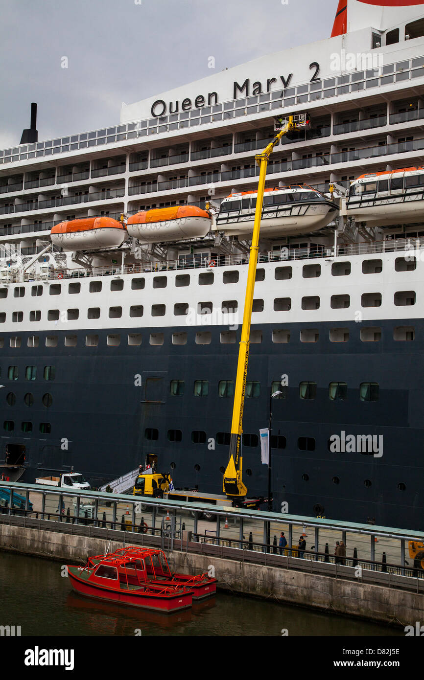 Liverpool, UK 17th May, 2013. Pilot boat and maintenance crew at the Cruise Liner Terminal where the Passenger ship registered in Bermuda Liner RMS Queen Mary 2 berthed on her visit to the City.  The Liverpool Cruise Terminal at Princes Parade is a 350-metre-long floating structure situated on the River Mersey enabling large cruise ships to visit without entering the enclosed dock system or berthing mid-river and tendering passengers ashore. The terminal was officially opened on 21 September 2007 by HRH The Duke of Kent when the Queen Elizabeth 2 berthed at the terminal. Stock Photo