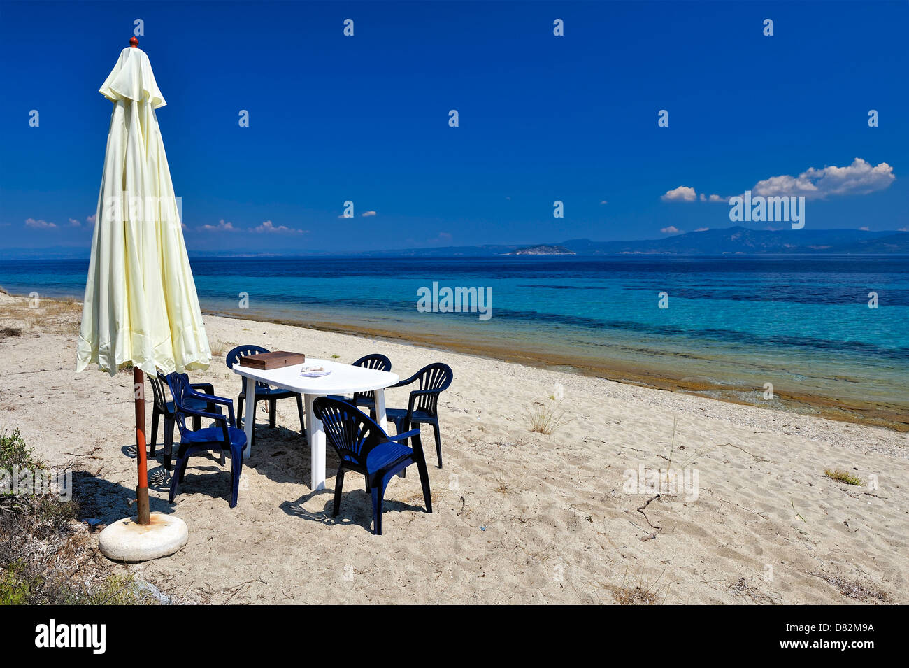Umbrell,table and six stools on the bezch Stock Photo