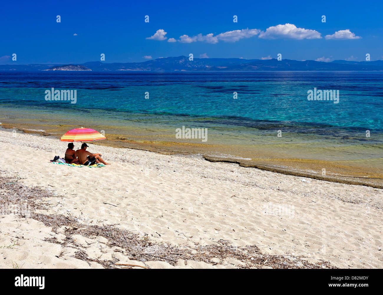 Two people on the beach with umbrela Stock Photo