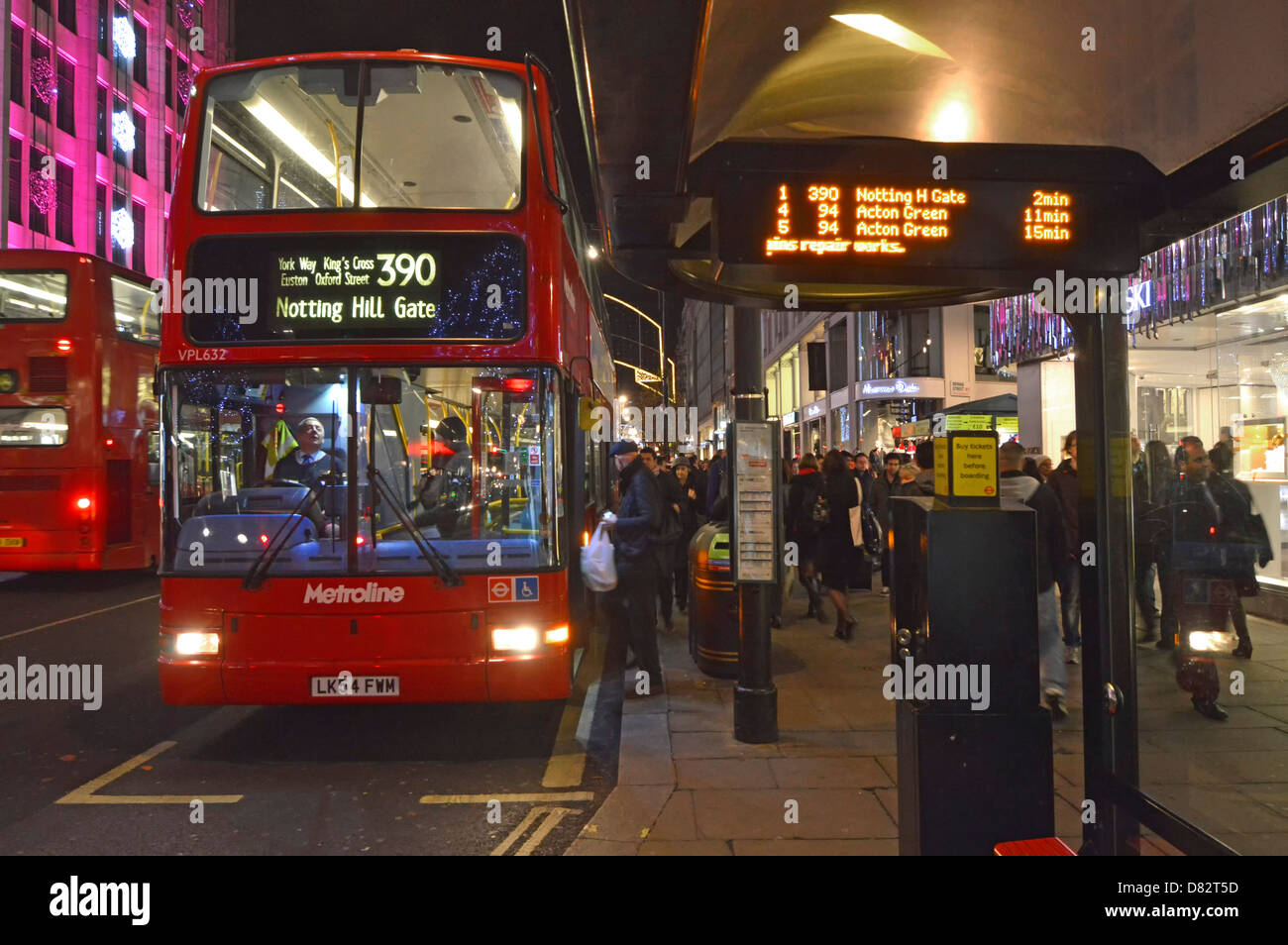 Bus stop shelter at night with people boarding London double decker bus